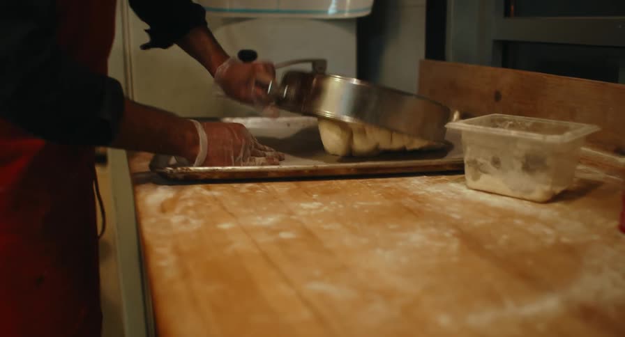 A bakery worker preparing dough for baking bread in a bakery kitchen