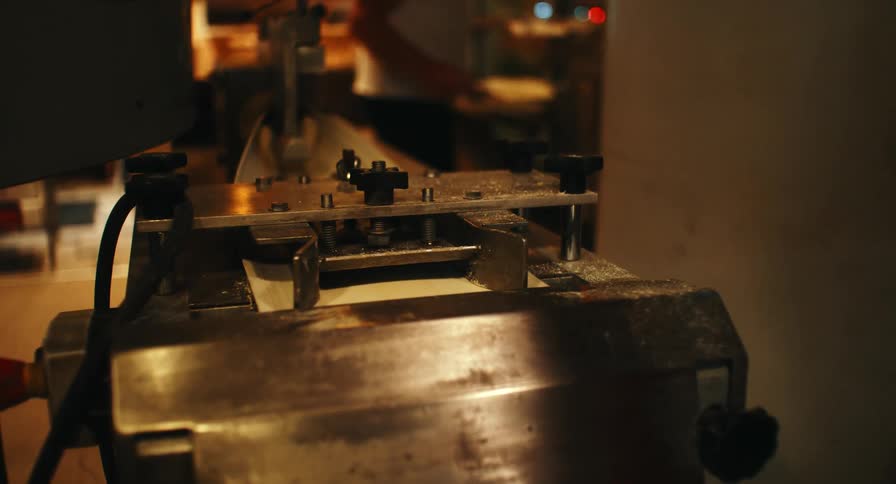 Bread dough being manually shaped on industrial baking equipment