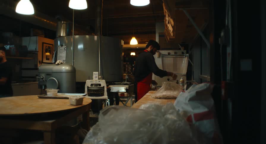Three bakery staff working together in a dimly lit commercial kitchen