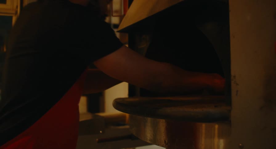 Two bakers baking fresh bread in a commercial kitchen with loaves inside an industrial oven