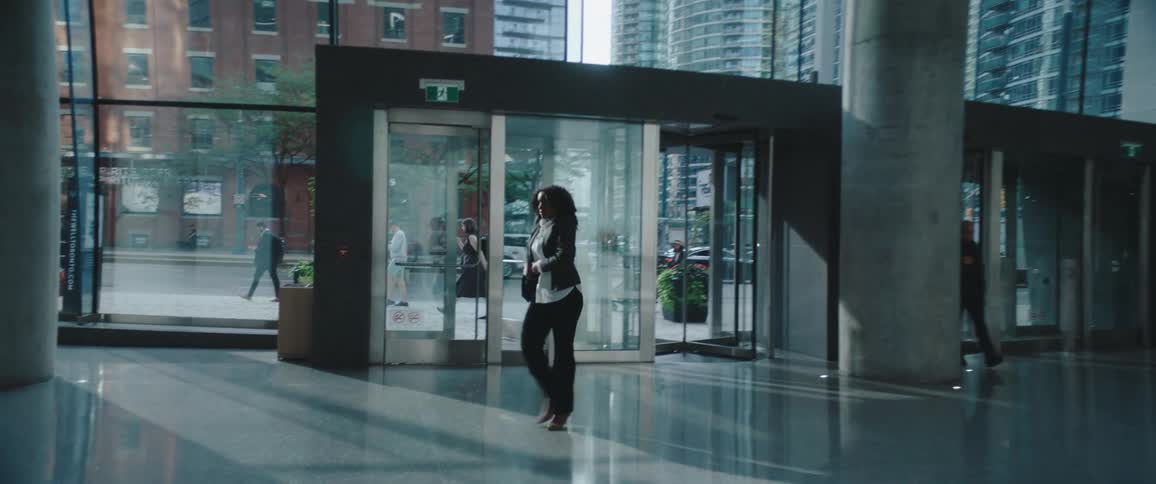 A woman walks into a modern office lobby through revolving glass doors