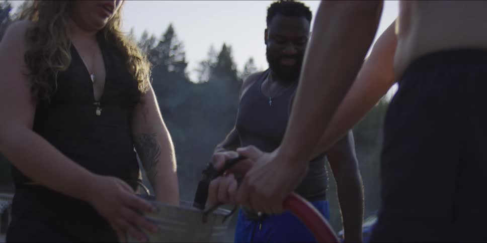 The woman holds a bucket while the man fills it with water