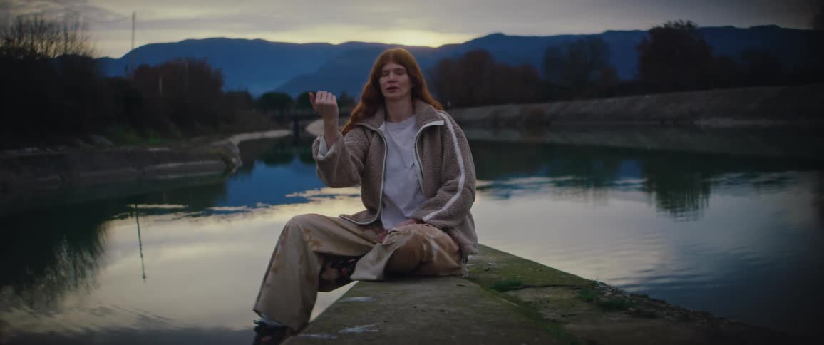 A woman sitting out near a lake