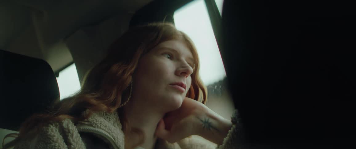Woman sitting in the back seat of a traveling automobile looking out the window