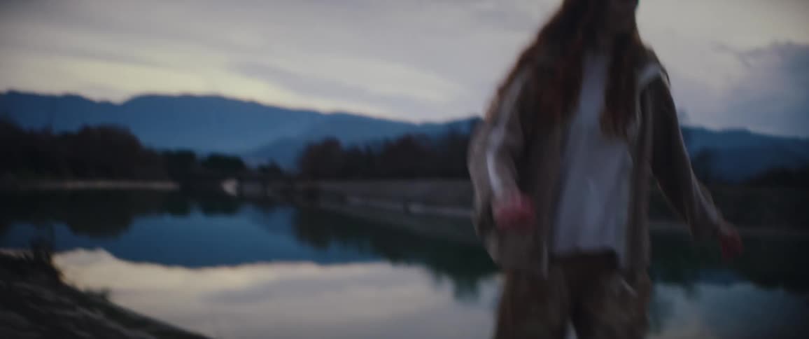 The woman is kicking rocks into the lake
