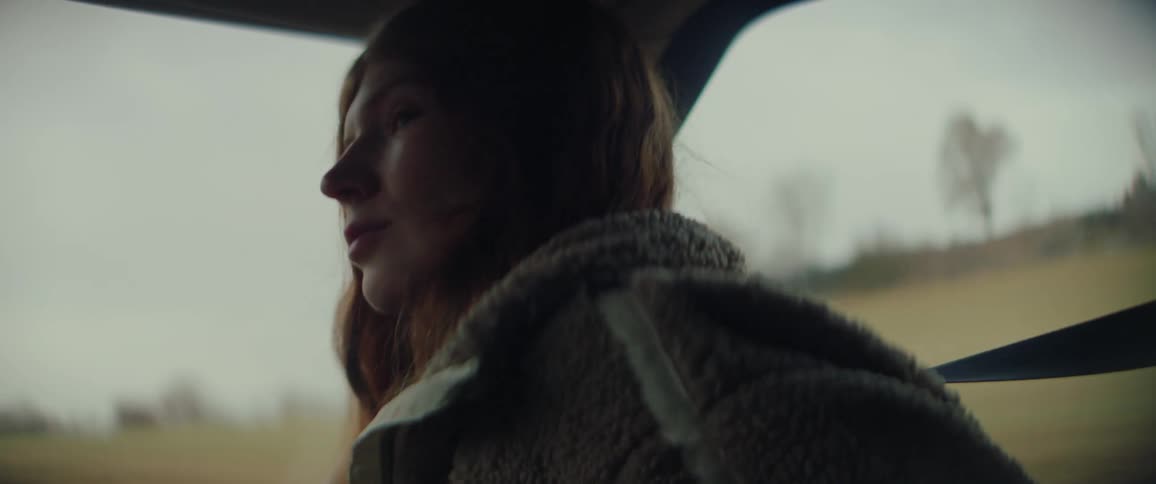Woman sits in the passenger seat of a traveling automobile looking around as they go