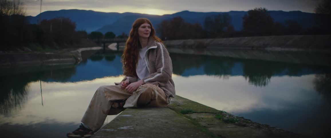 A woman sitting next to a lake