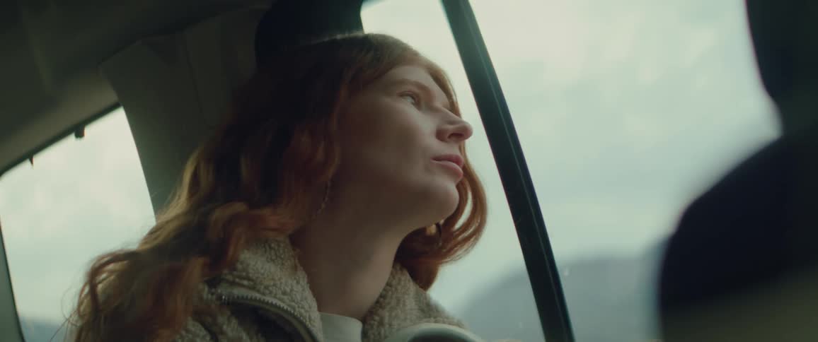 A woman sits and looks out the window of a vehicle while traveling