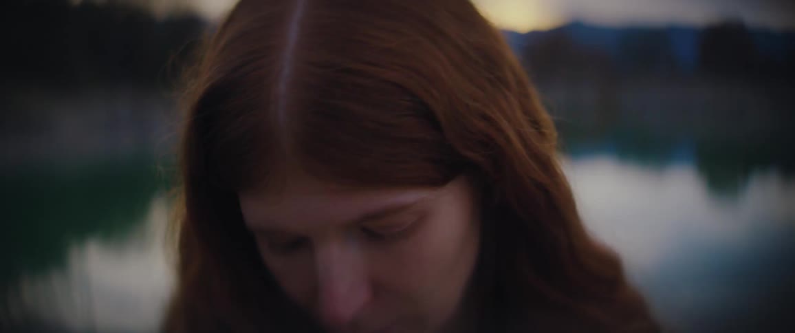 Young adult woman looking around at a natural setting with a contemplative facial expression outdoors during dusk or dawn