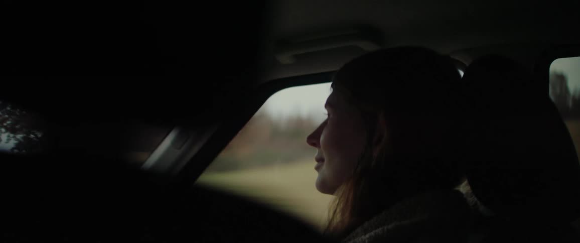 Female passenger riding in a car during an autumn road trip smiles at the driver