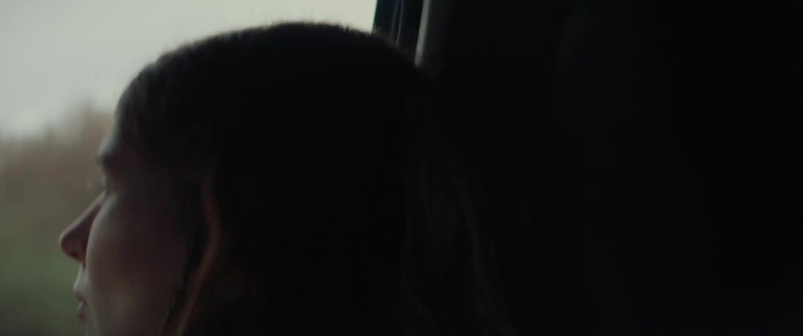 The woman is riding in the car and looking out the window