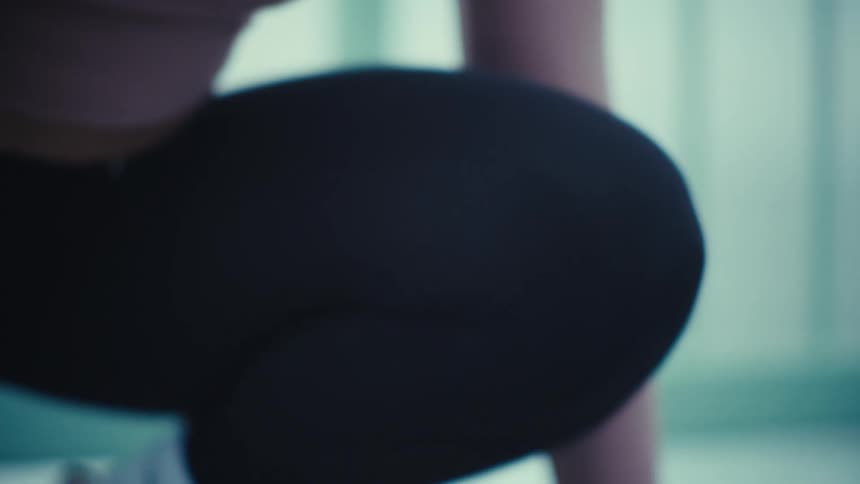 A woman with curly hair focuses intensely as she prepares for a run on an outdoor track the camera pans down to show her hands and feet in a starting position ready to launch forward
