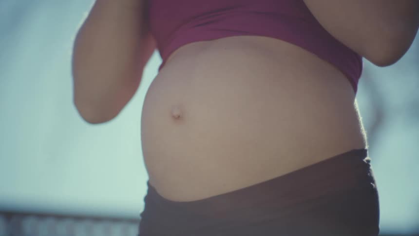 Expectant mother exercises with a weight while outdoors on a summer day