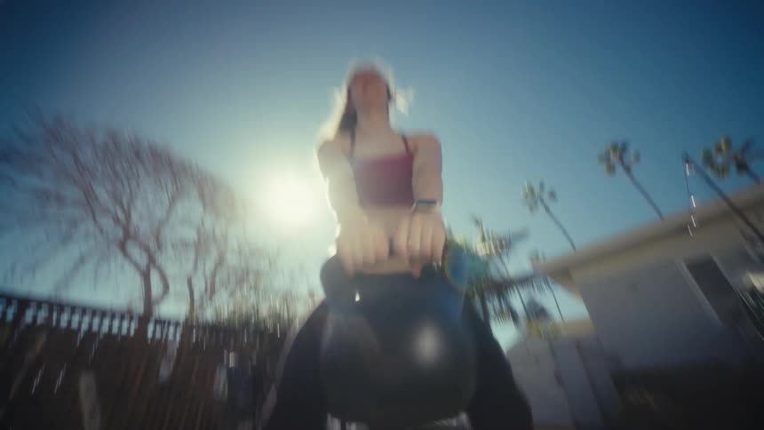 Woman exercises with a kettlebell in her yard