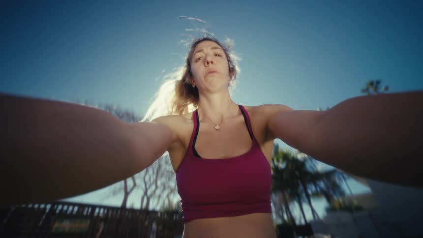 Expectant mother lifts and swings a weight while exercising in her backyard on a sunny summer day