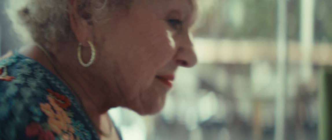 Woman sits at a table with a tablet computer as she looks at paperwork