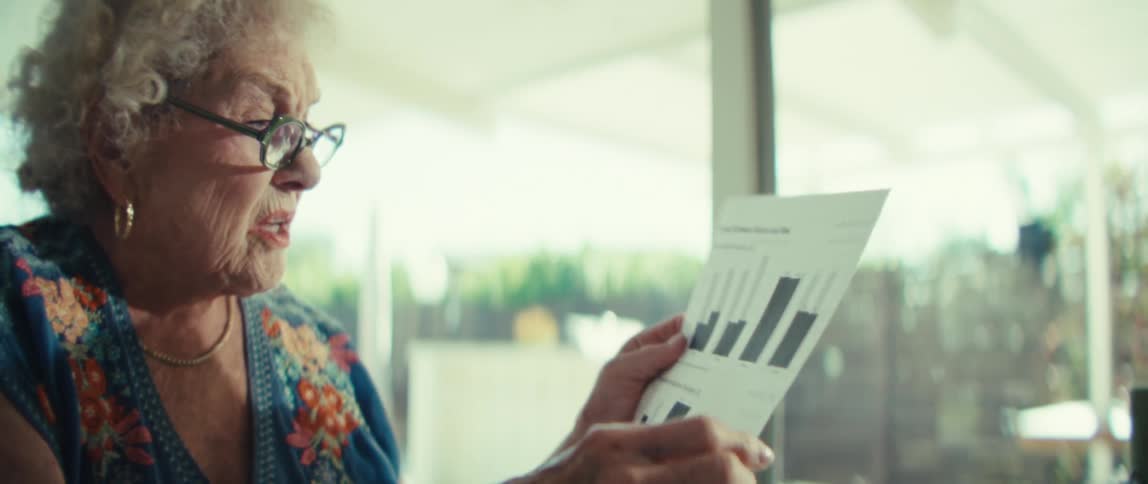 An elderly woman intently discussing or explaining financial data presented on a document