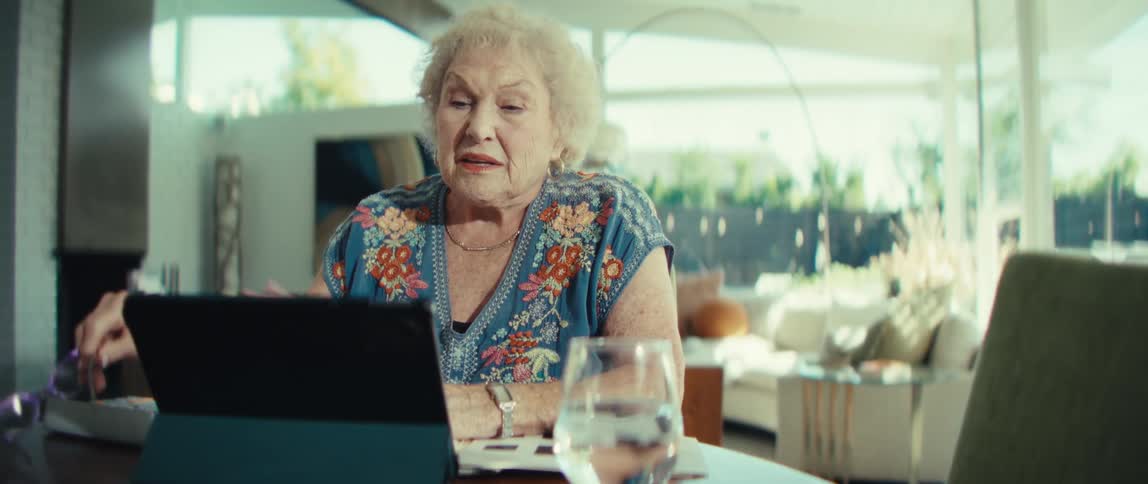 The woman takes off her glasses while talking on her tablet