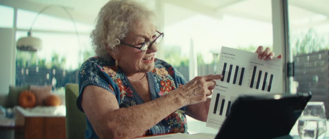 An elderly woman gives a chart presentation via an electronic tablet