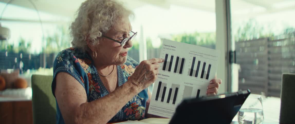 The woman is pointing at paperwork while talking on a tablet