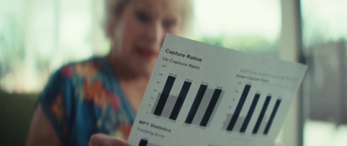 An elderly woman looks surprised and concerned while reviewing a financial document with bar charts