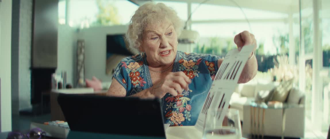 An elderly woman on a video call turns concern into triumph while presenting data charts