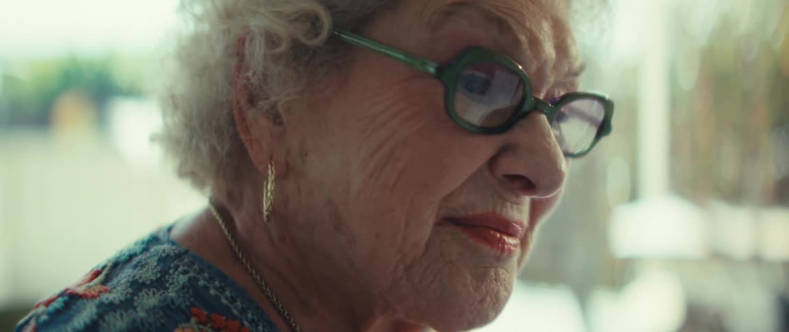 An elderly woman reviews financial documents and smiles contentedly