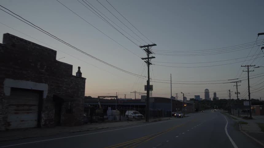 A car drives on a city road at sunset