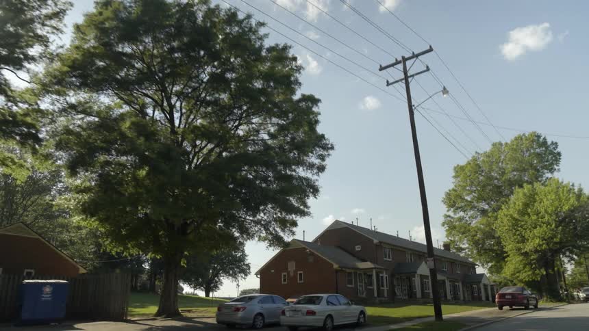 Homes line a residential street as the sun shines overhead