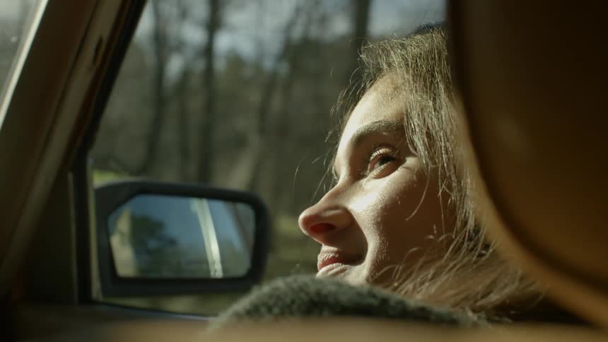 A woman in a car turns to the driver and smiles