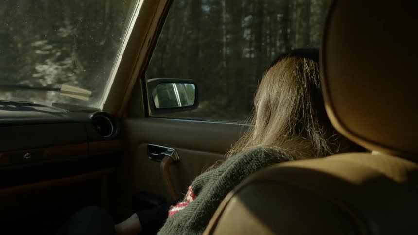 A woman smiles as a vehicle drives through a tree lined road