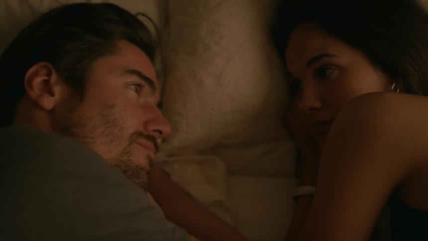 Man and woman laying in bed looking into each others eyes