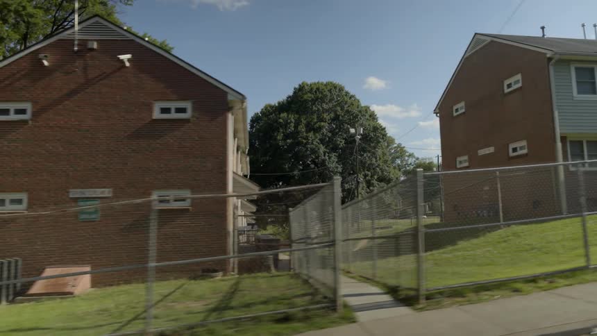 A car passes by rows of houses