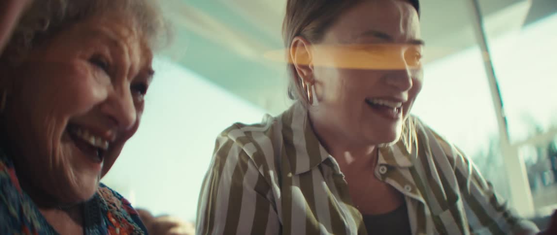 A younger woman and an elderly woman react with joyous surprise while looking at something together