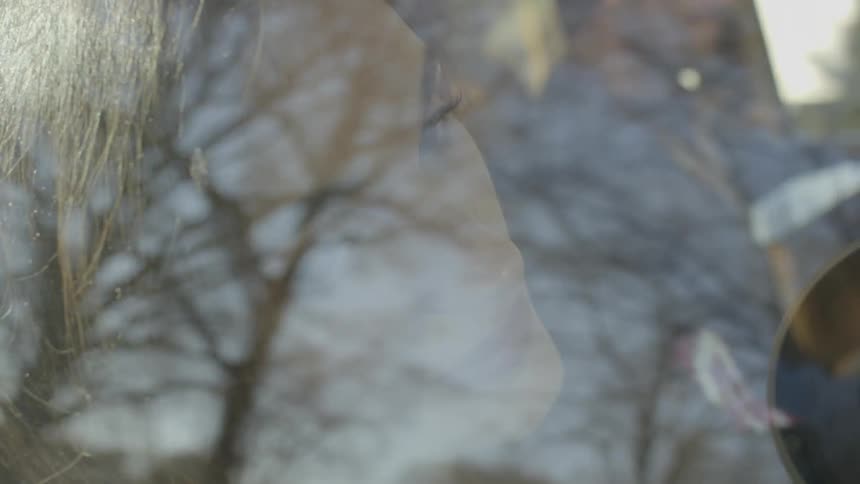 A woman leans against the window as a man drives