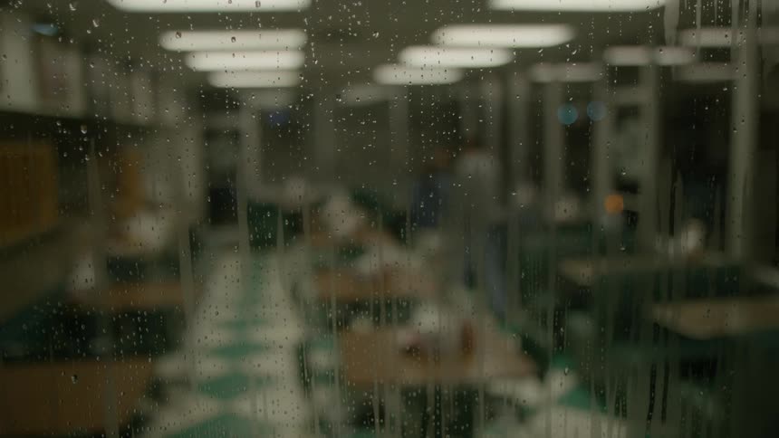 Raindrops running down window outside diner at night