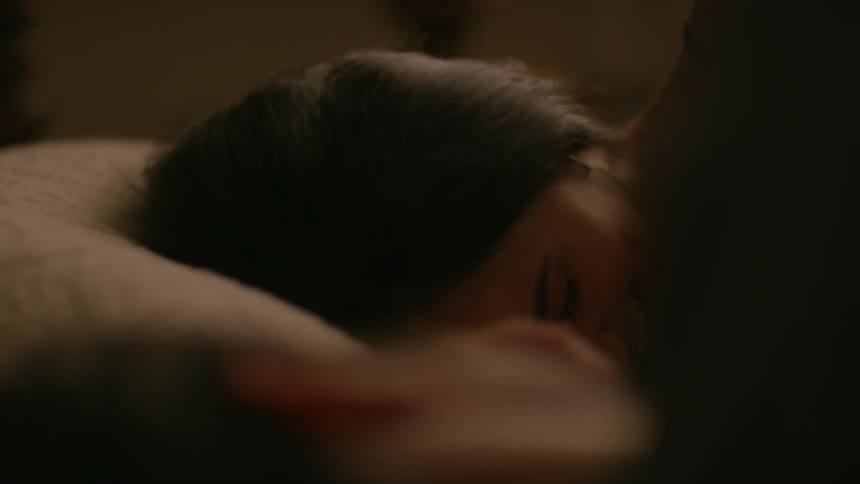 A woman talks and laughs with someone laying next to her