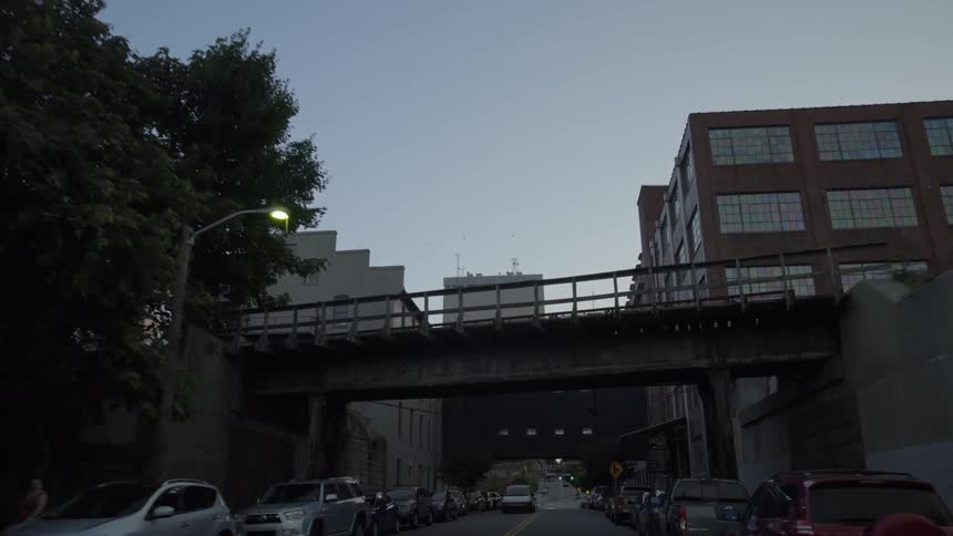 Vehicles line the busy city road under a bridge