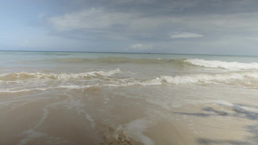 Waves coming ashore on a beach on a cloudy day