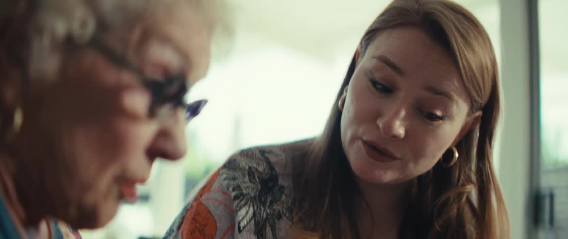 A younger woman helps explain a calculation to an elderly woman