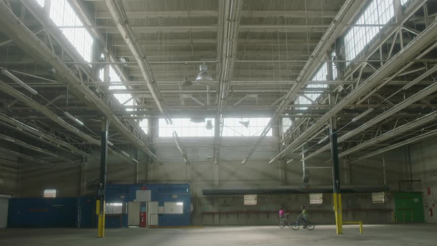 Children ride their bicycles in an empty warehouse