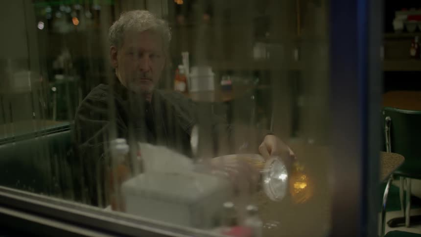 A man sits at a booth in a restaurant