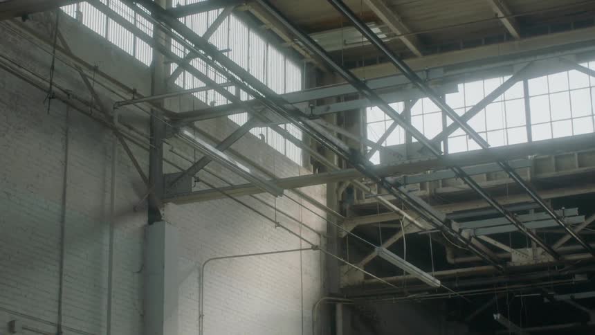 Lights and rafters hang on the upper level of an abandoned factory