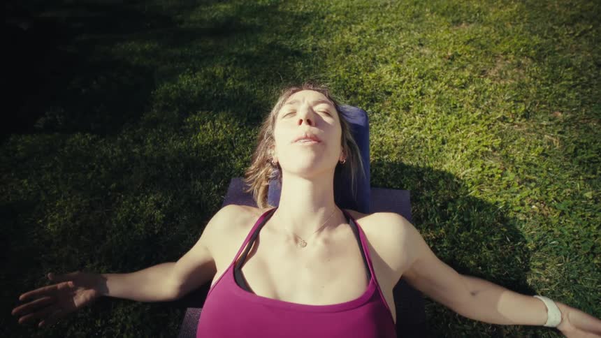 Adult woman lying down and stretching her arms outdoors during day time