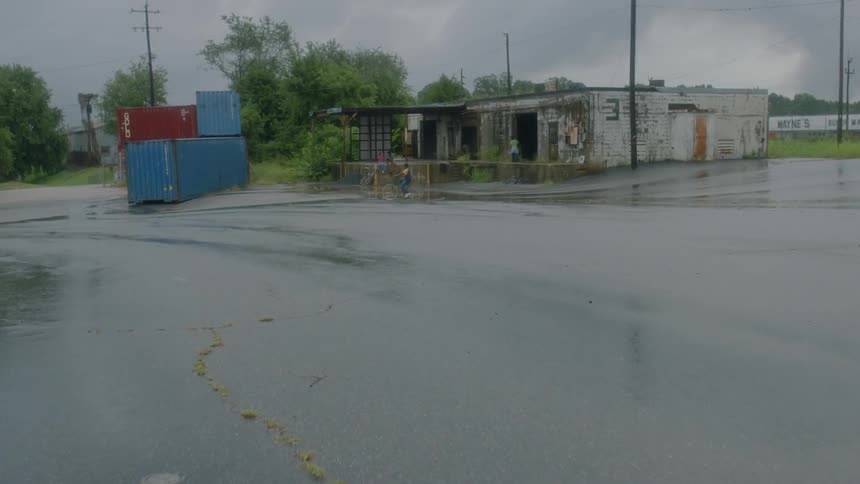 A child rides a bicycle outside a dilapidated building