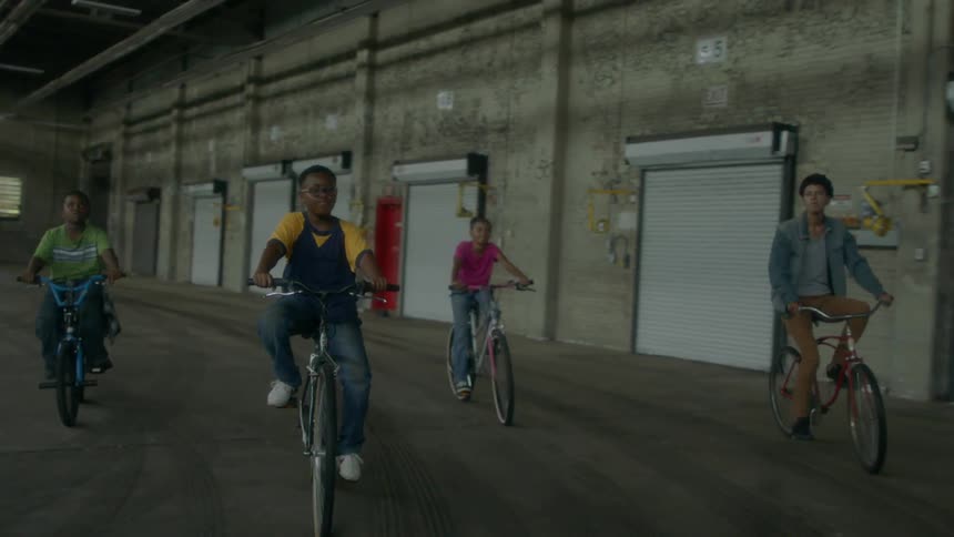 Boys ride bicycles in a warehouse
