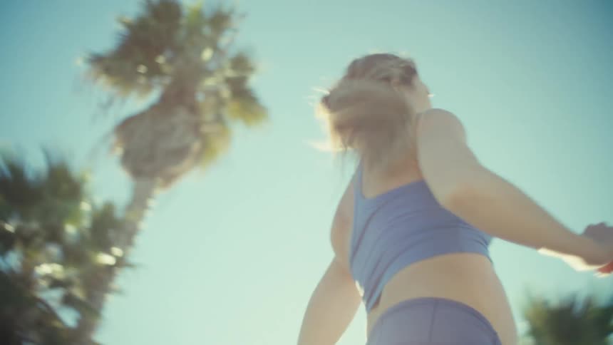 A pregnant woman running in athletic wear through a park under bright sunlight
