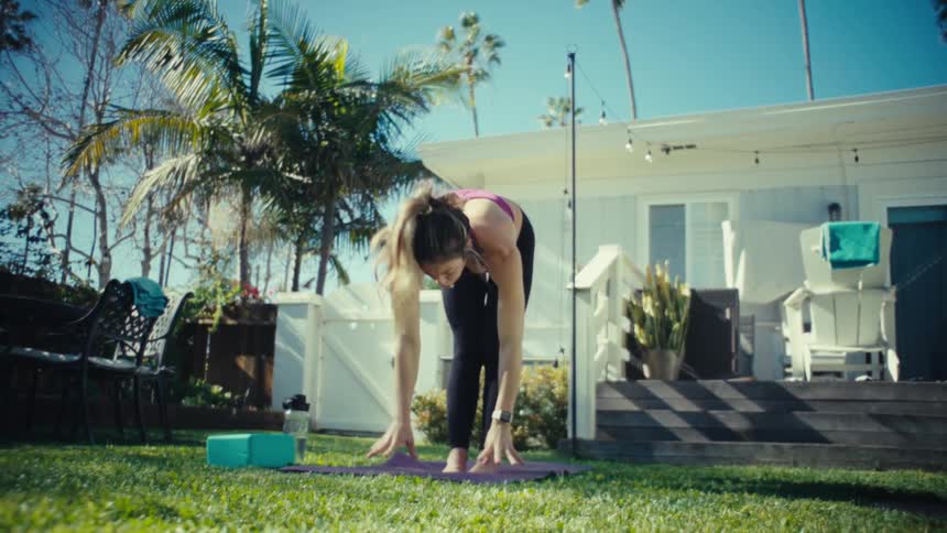 A pregnant woman practicing yoga and stretching for peace and relaxation on a sunny lawn