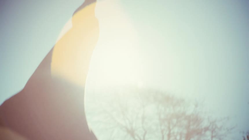 A pregnant woman practicing sun salutation on a yoga mat in an outdoor park on a sunny day