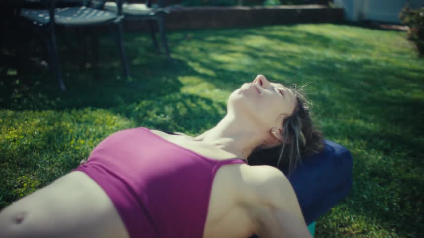 Woman lying on a mat in her yard stretching